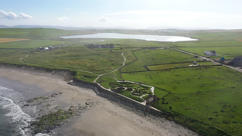 View from above Skara Brae showing the view over Loch Skaill behind the settlement.