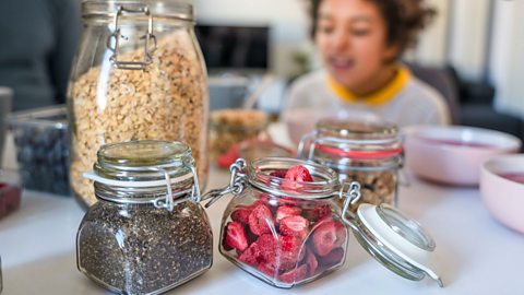 child looks at jars of healthy grains and fruits