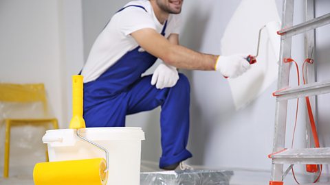 Man painting a wall with a roller