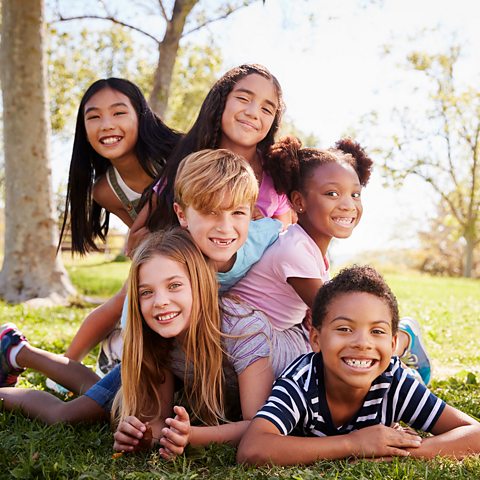 A picture of a group of children smiling in a park. 