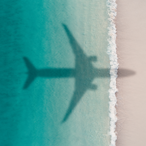 An image of a plane flying over the sea meeting the beach