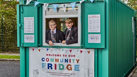 Two school age children work inside a community fridge