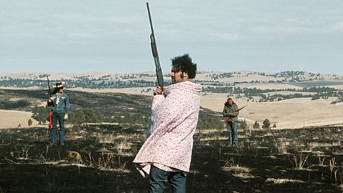 A photograph of a man holding a rifle at Wounded Knee