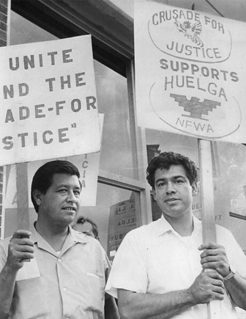 A photograph of two men holding up protest signs