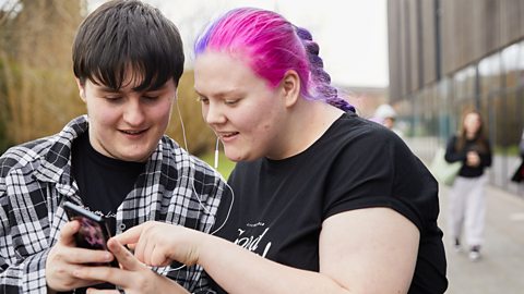 An image of a girl and boy listening to music on their smart phone. 