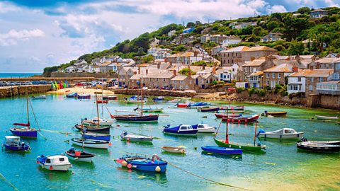 Mousehole in Cornwall. A village on the coast with boats in the harbour.