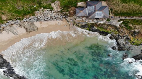 A bay with a sandy beach and rocks in Cornwall.