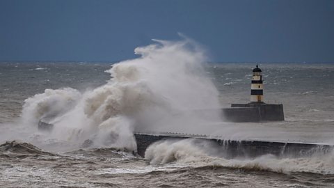 Waves crashing around a lighthouse in Seaham, Durham