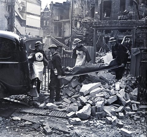 Volunteer wardens carrying a civilian patient on a stretcher from a bomb damaged building.