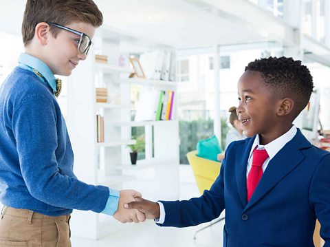 Two children shaking hands in an office. 