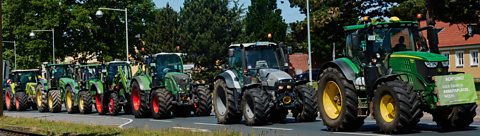 A line of tractors driving down the street