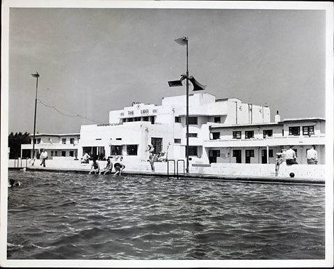 A black and white photograph of an outdoor swimming pool at a holiday camp.