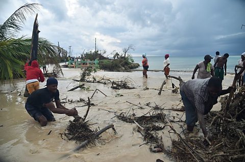 People stood in flood water surrounded by twigs and branches