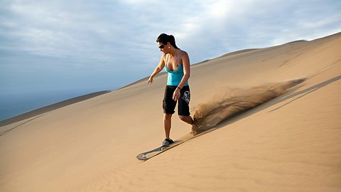 A woman sandboarding in the desert