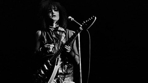 Singer Siouxsie Sioux, of group Siouxsie and the Banshees, plays guitar as she performs on stage.