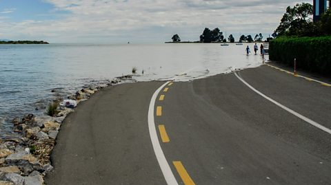 Water covers a road due to rising sea levels.