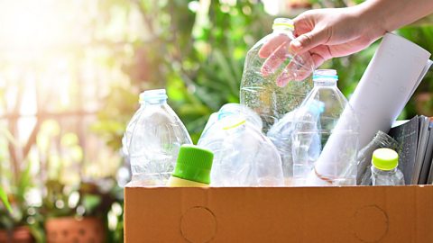 A cardboard box full of plastic bottles and paper ready to be recycled. 