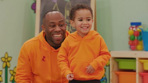 A dad and his son wear matching jumpers in the toddler club. They are both smiling.