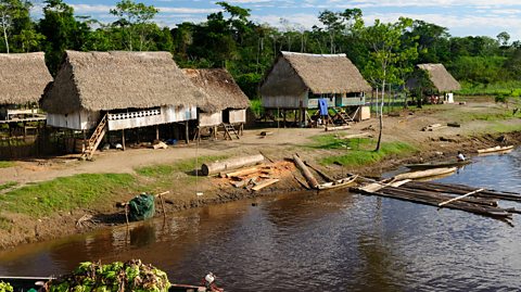 A wooden home on top of long wooden stilts next to water.