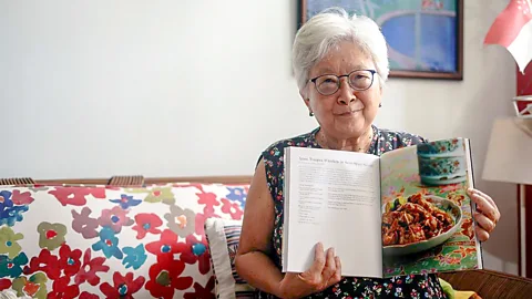 Rachel Phua Lee Geok Boi holding her recipe book, In a Straits-Born Kitchen (Credit: Rachel Phua)