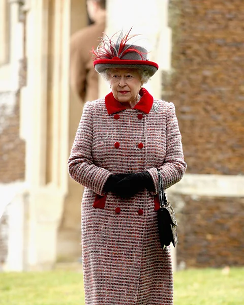 Getty Images A classic tweed coat with a festive red trim was the outfit for a Christmas Day church service at Sandringham – the handbag is by Launer (Credit: Getty Images)