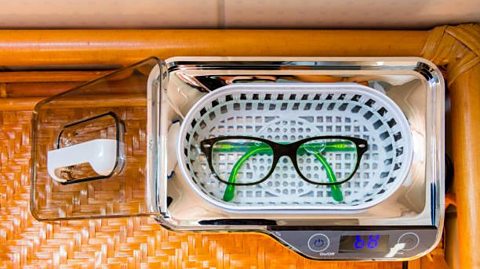 A pair of glasses inside an ultrasonic cleaner with the lid  glasses are under water inside the machine 