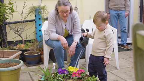 A little boy and his grandparents playing in the garden.