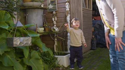 A little boy playing hide and seek with his grandma - he's pointing to where he thinks the butternut squash is hidden in the garden.