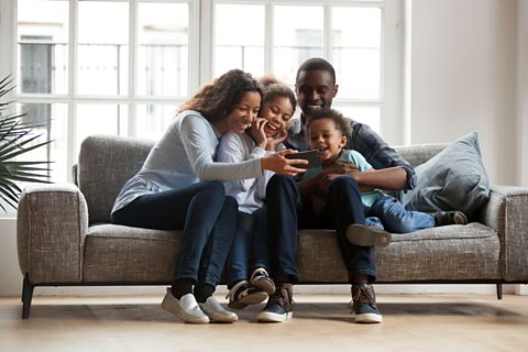 Family of four play on tablet together.