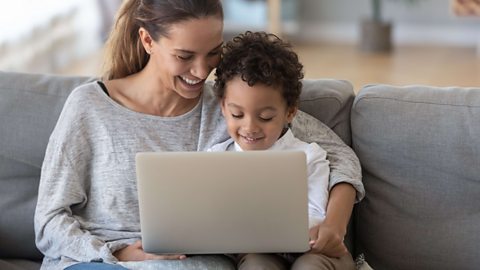 Woman and child play on laptop together.