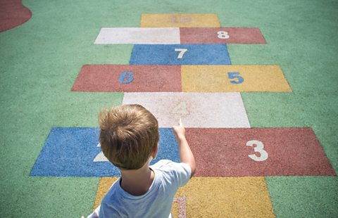 Child learns about numbers using a hopscotch.