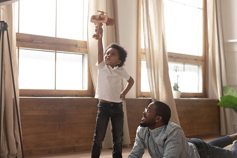 Boy and dad play with a toy plane.