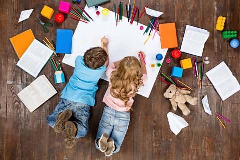 Two children drawing on the ground.