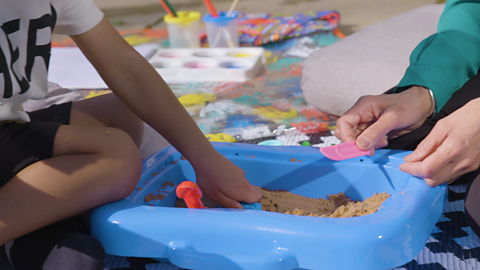 A child's hands digging in sand.