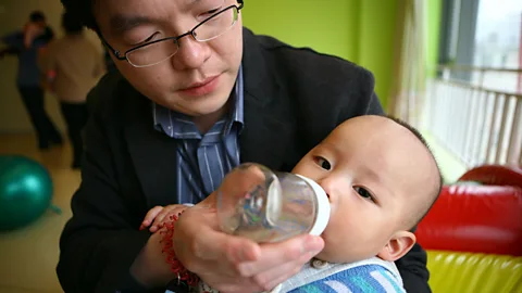 Gou Yige/AFP via Getty Images A dad bottle-feeds his son in a pre-school class in Beijing (Credit: Gou Yige/AFP via Getty Images)