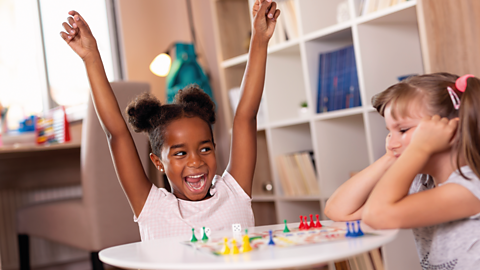 Two girls play a board game.