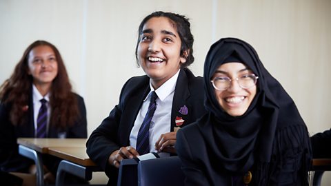 A group of secondary school students smile in the classroom