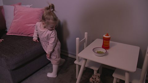 A little girl spotting a tiger toy that's hidden under a table.