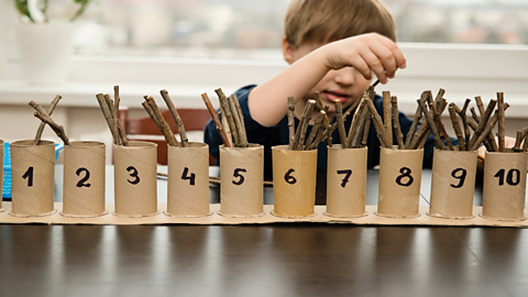 Boy organises sticks into number order.