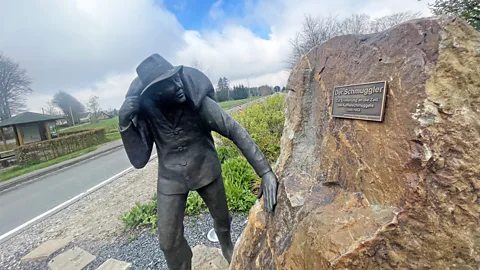 Larry Bleiberg The town of Mutzenich honours criminals with a bronze statue of a man with a sack of coffee over his back (Credit: Larry Bleiberg)