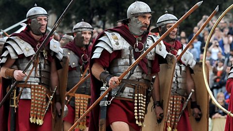 Roman army re-enactors wearing armour and holding javelins. 