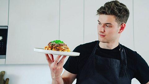 Sam Way/Samseats holding a plate of pasta with beef ragu