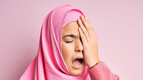 A woman holds her eye in pain