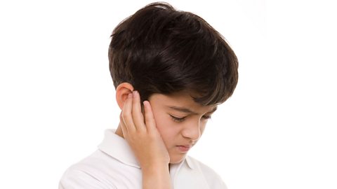 A boy touches his ear in pain