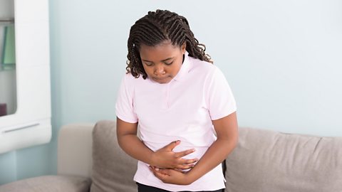 A girl touches her stomach in pain