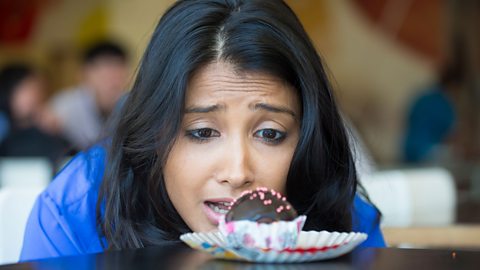 woman stares at chocolate truffle desperately wanting it