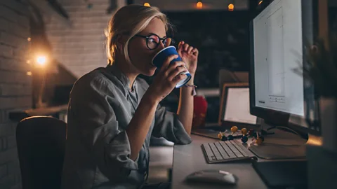 Getty Woman drinking coffee as she works