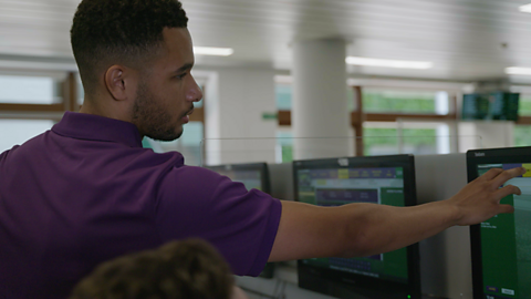 A photograph of Jed, a press office assistant at Wimbledon, showing a journalist how to use the touch-screen computers on site at Wimbledon.