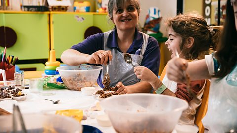 One of the play specialists at Great Ormond Street hospital making rice crispy cakes with a young girl.