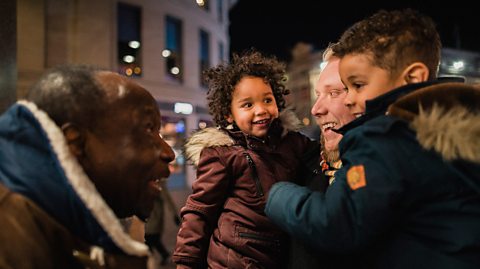 A dad and his 2 little boys meeting grandad in the street.